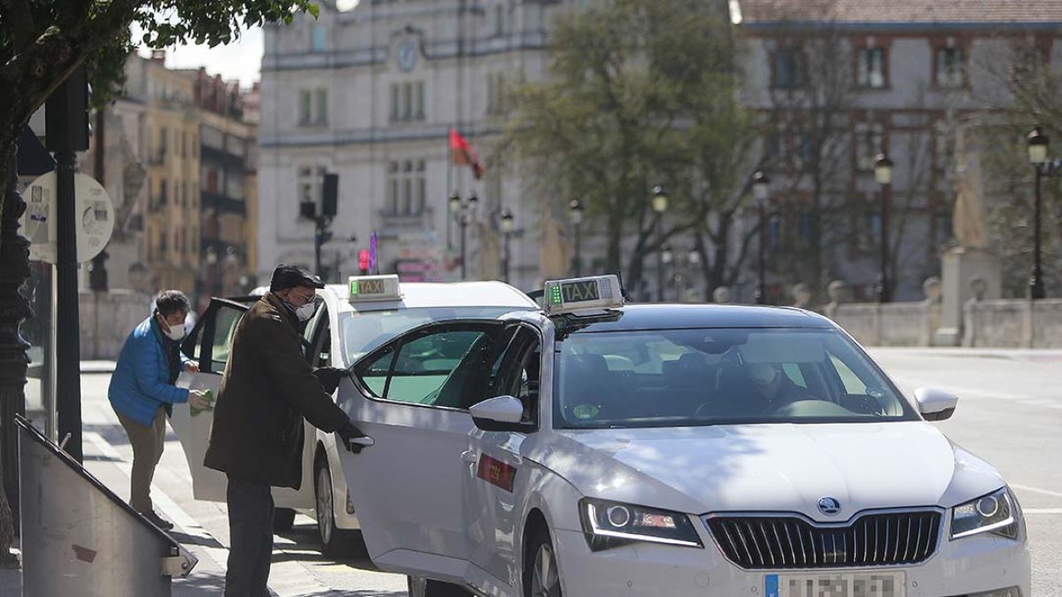 Dos personas mayores con mascarilla abordan sendos taxis en la parada de la plaza del Cid. RAÚL OCHOA
