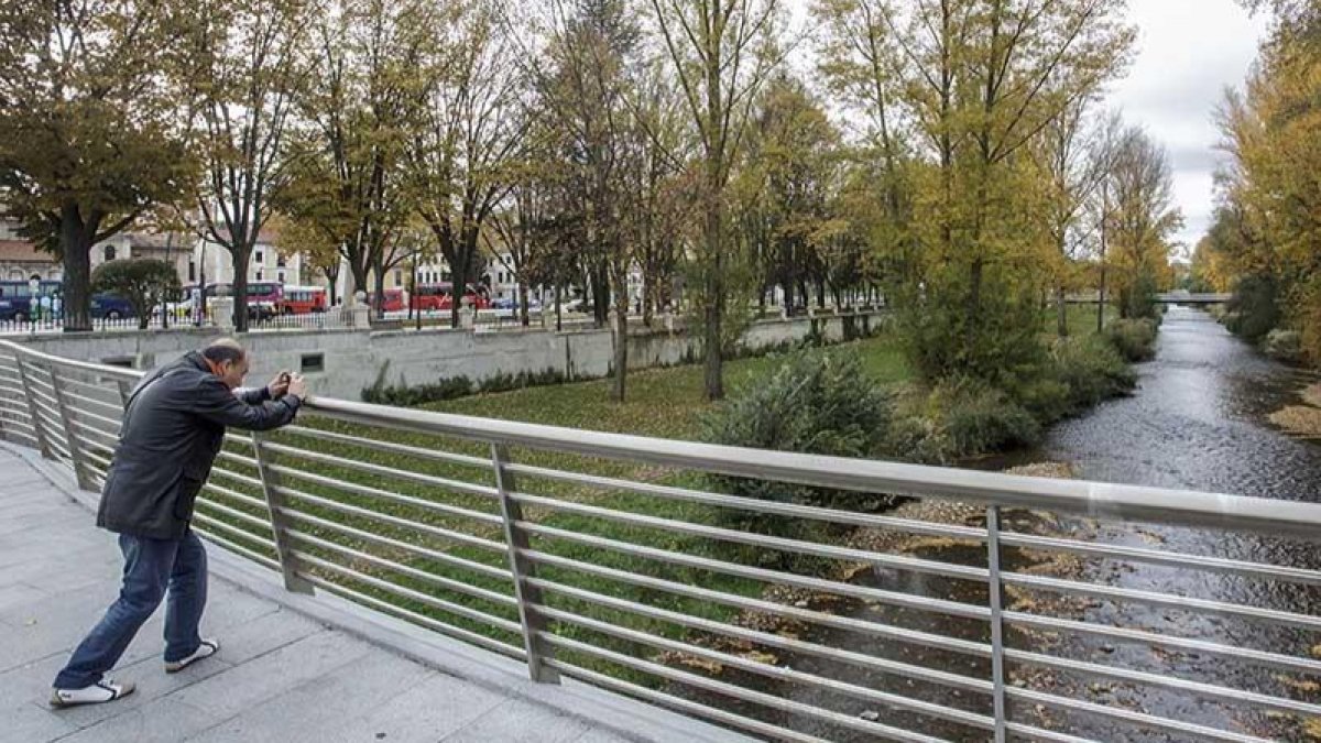 Un hombre hace una foto al río Arlanzón a su paso por la capital burgalesa. ECB