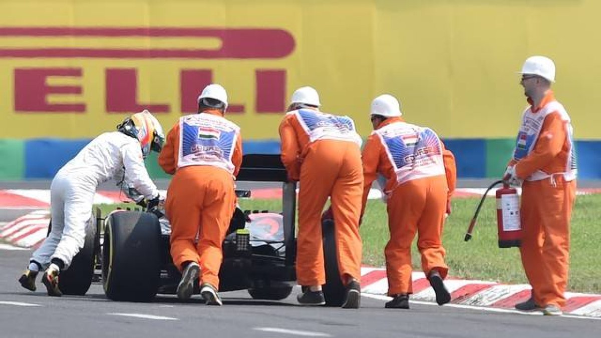 Alonso empuja su coche hasta el 'pit lane'.-Foto: ANDREJ ISAKOVIC / AFP