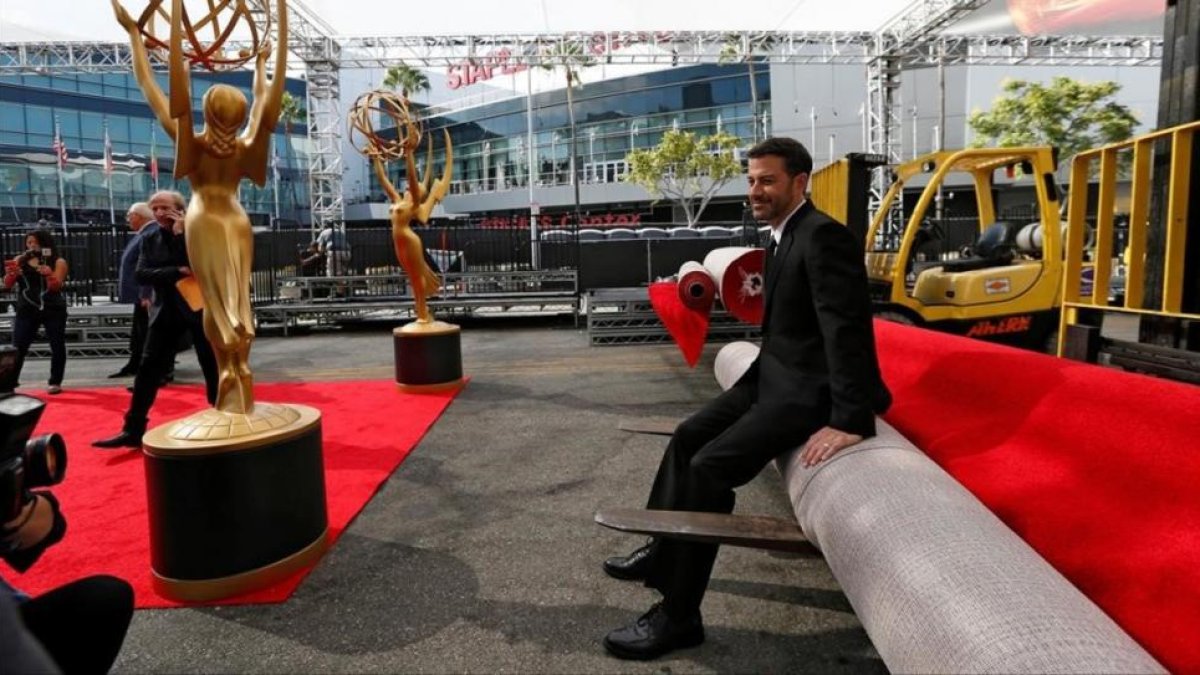 El presentador de la gala, Jimmy Kimmel, posa para la prensa, sentado sobre la alfombra roja de los 68º premios Emmy, aún enrollada.-MARIO ANZUONI / REUTERS