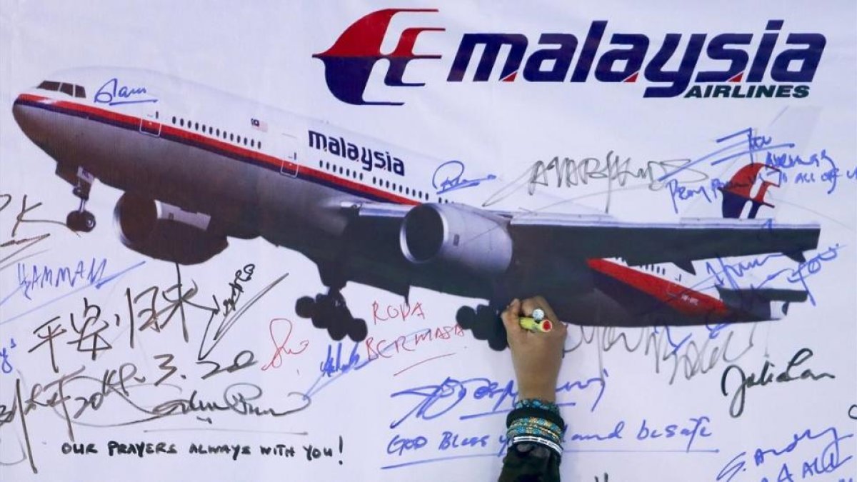 Una mujer escribe un mensaje de solidaridad con los pasajeros del vuelo desaparecido de Malaysia Airlines en Kuala Lumpur en el 2014.-/ SAMSUL SAID (REUTERS)