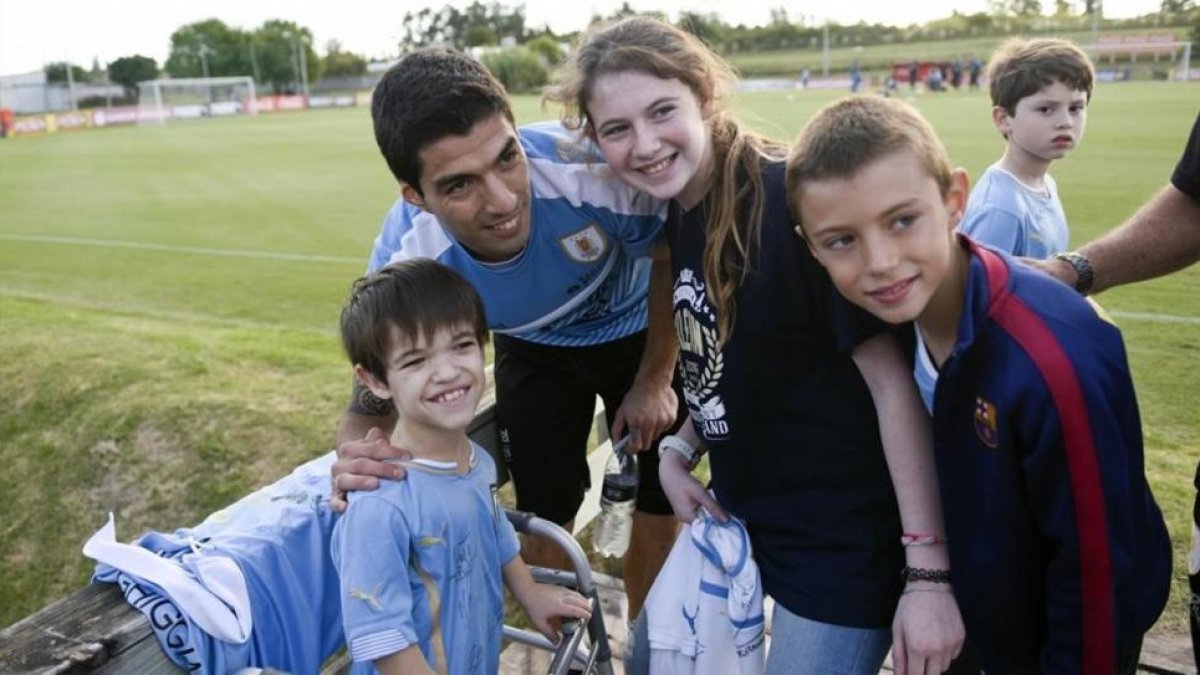 Luis Suárez posa con una jóvenes aficionados tras su primer entrenamiento con la selección uruguaya.-AP / MATILDE CAMPODONICO
