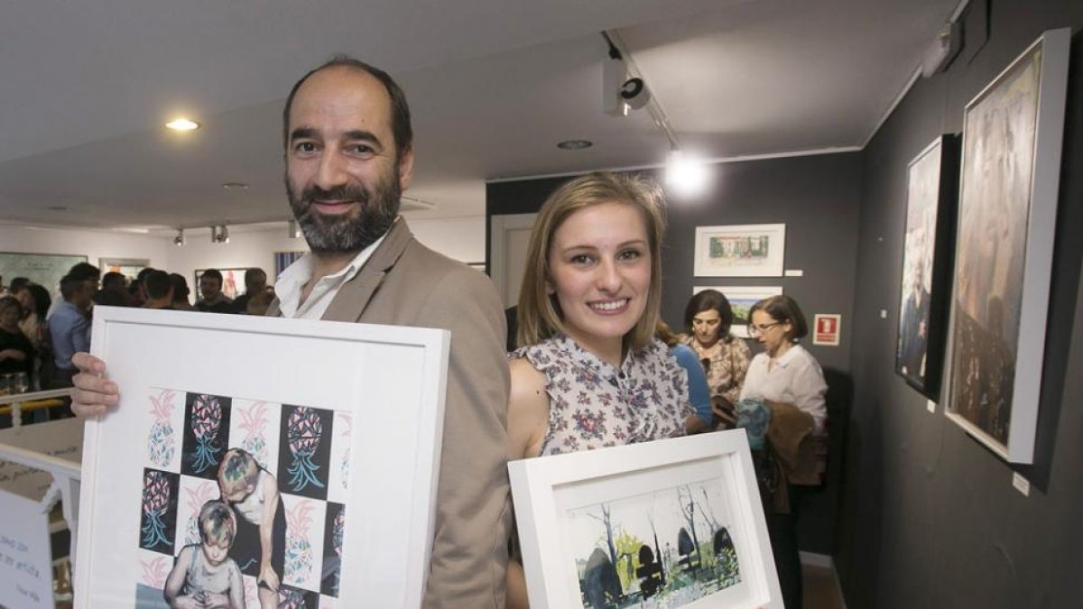 Ismael Alí de Unzaga y Elvira Mateos sujetan un cuadro del otro durante la inauguración de la exposición el pasado jueves.-Raúl Ochoa