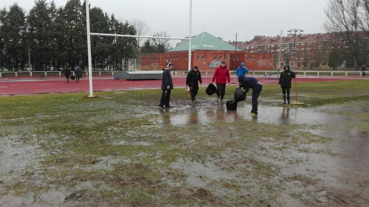 Jugadores y colaboradores delAparejadores RC achican agua antes de concretarse la suspensión del choque, ayer.-ECB
