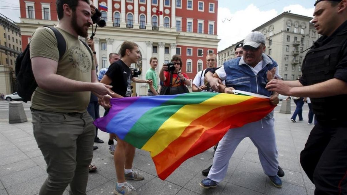 Un hombre intenta arrebatar una bandera de la comunidad homosexual a unos manifestantes en Moscú en el 2015.-REUTERS / MAXIM ZMEYEV