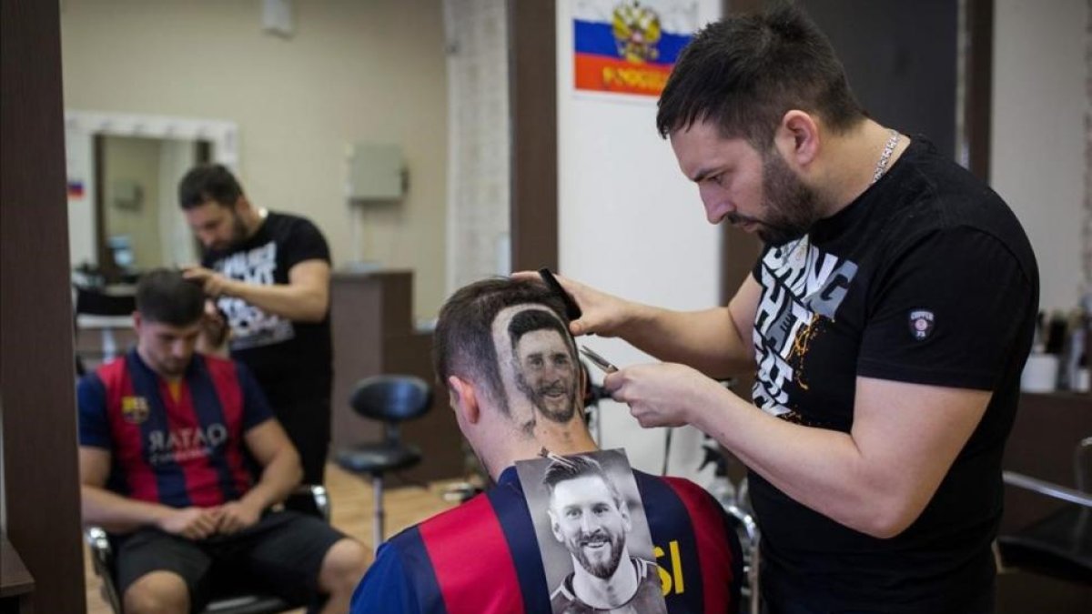 Mario Hvala, en plena tarea de esculpir el retrato de Messi en la cabeza de un seguidor del Barça de Novi Sad.-/ AFP
