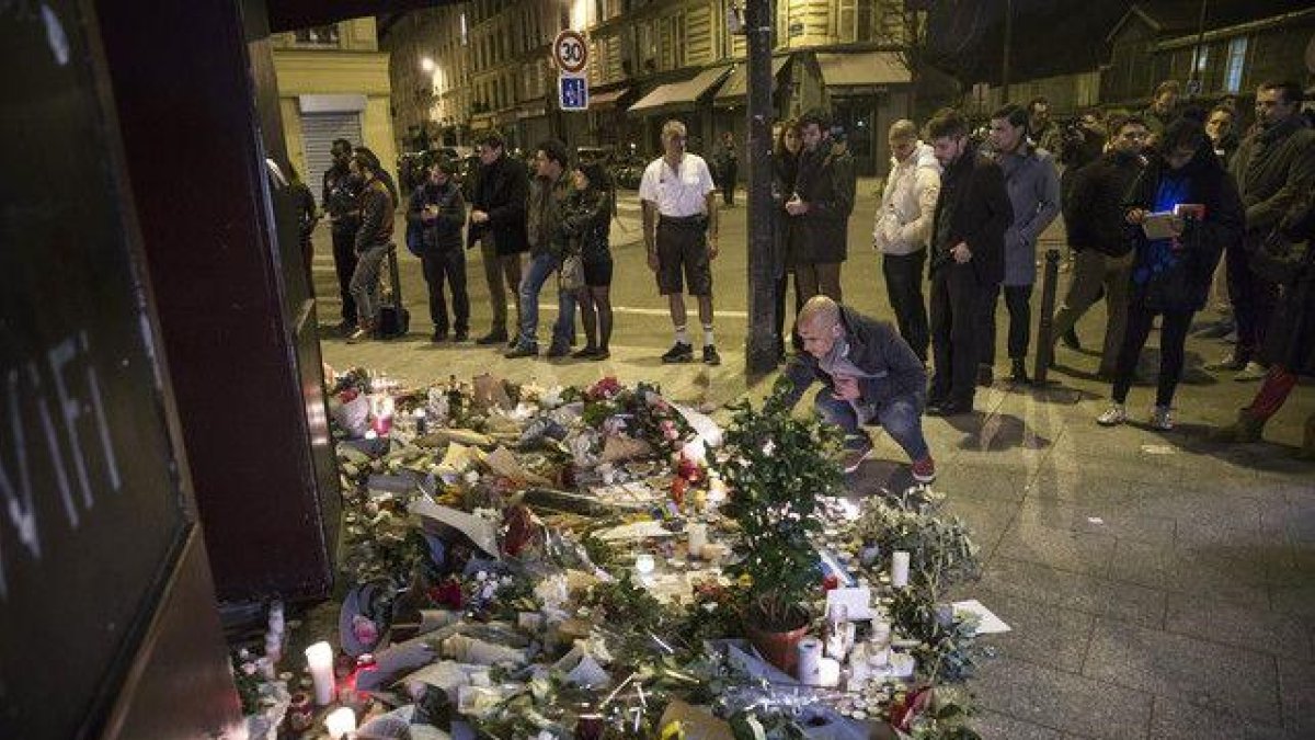 Los parisinos dejan flores y velas en honor a las víctimas de los atentados, en el café Carillon, en París.-EFE