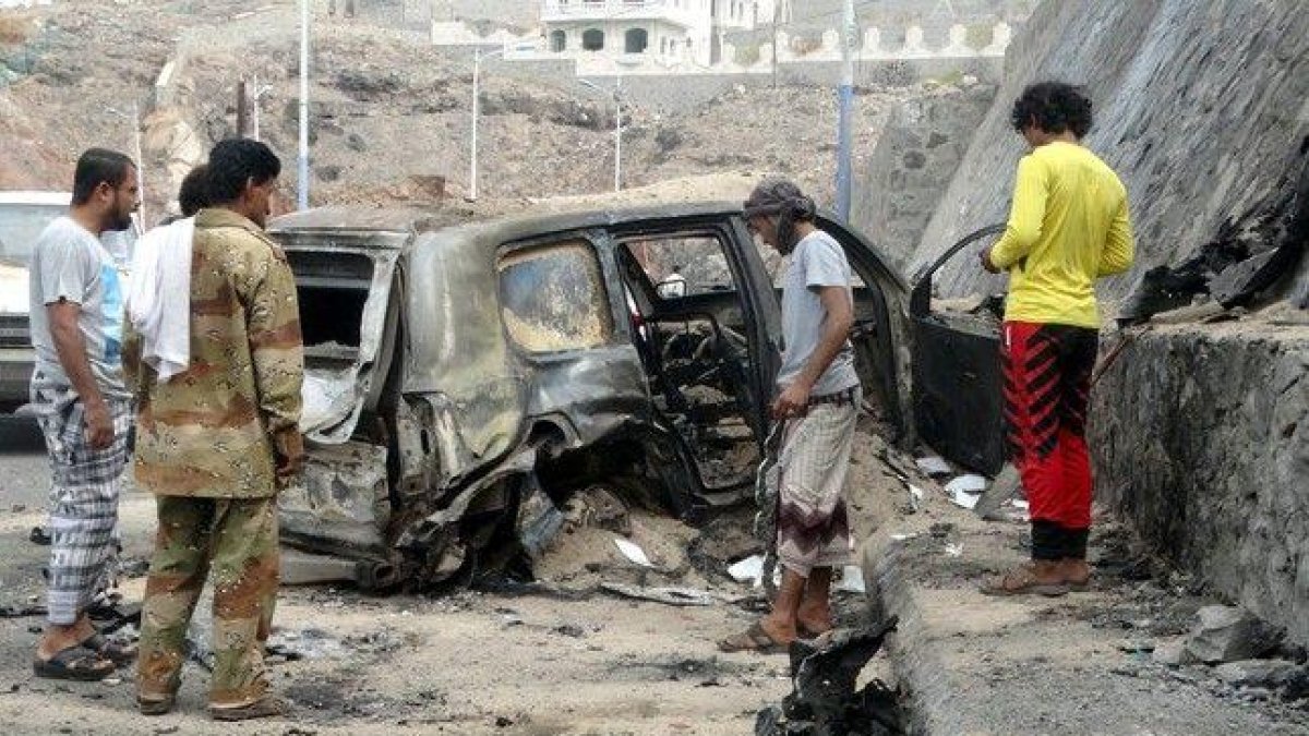 Varias personas contemplan los efectos del atentado con coche bomba en el que ha muerto el gobernador de Aden.-REUTERS