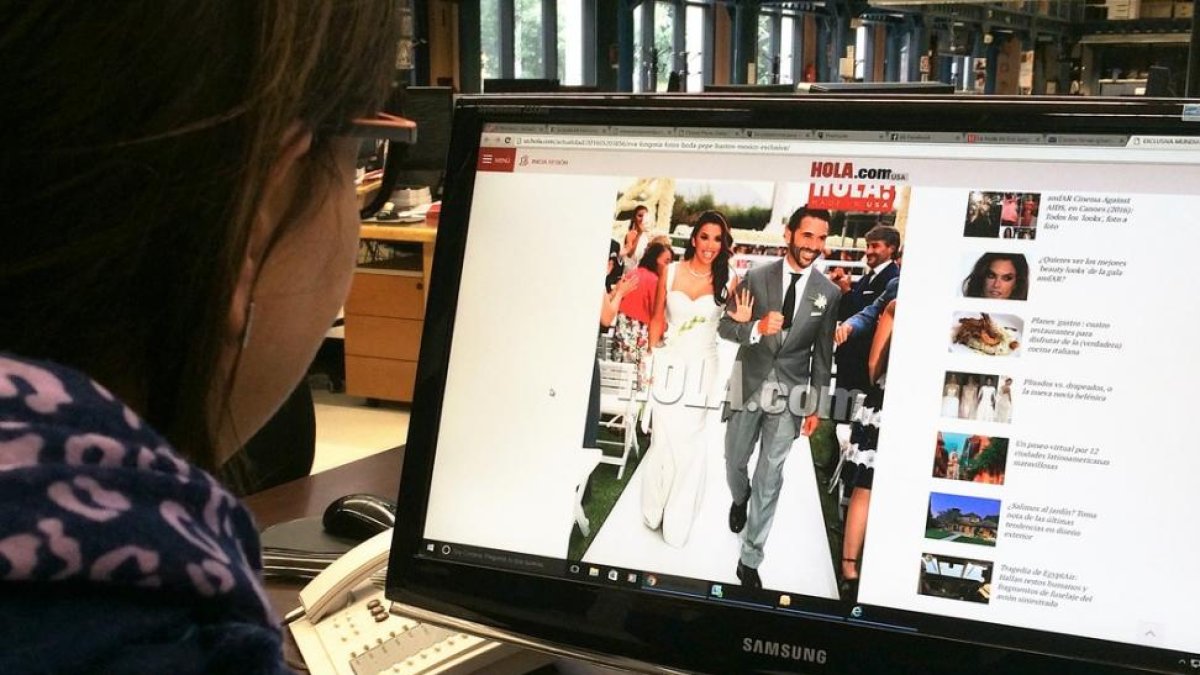Una lectora mira la foto exclusiva de la revista '¡Hola!' de la boda de Eva Longoria y Pepe Bastón, este sábado en Valle de Bravo (México).-EL PERIÓDICO