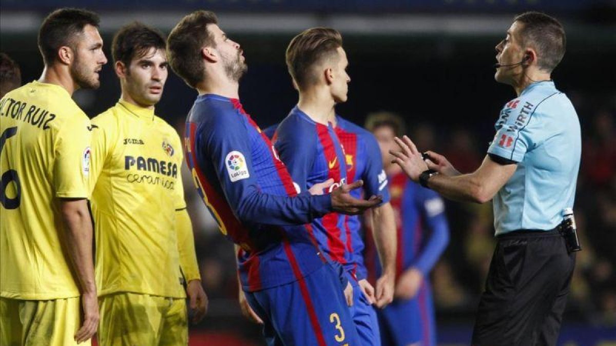 Piqué discute con el árbitro del encuentro entre el Villarreal y el Barcelona.-MIGUEL LORENZO