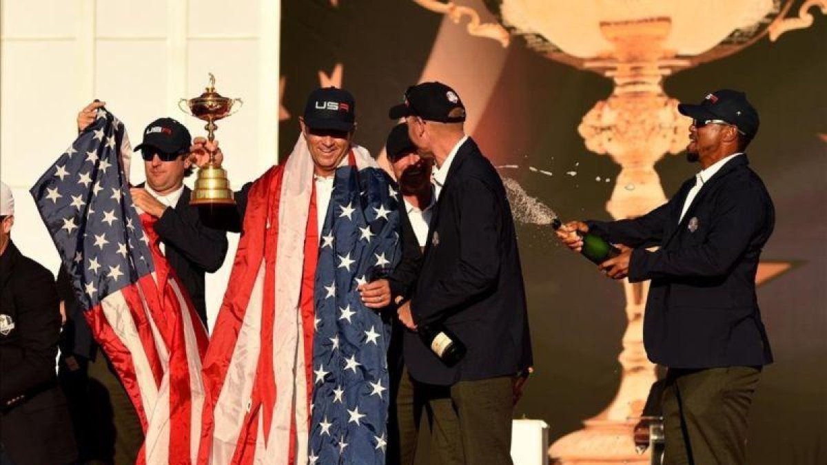 El capitán del equipo estadounidense Davis Love y su vicecapitánTiger Woods celebran en la ceremonia de entrega del trofeo.-TIMOTHY A CLARY / AFP