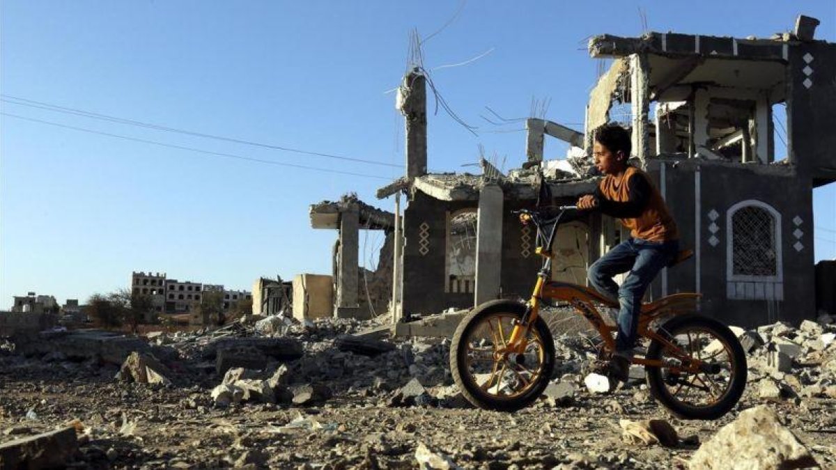 Un niño yemení pasea con su bicicleta junto a los escombros de una vivenda en Saná destrozada por los bombardeos aéreos.-YAHYA ARHAB (EFE)