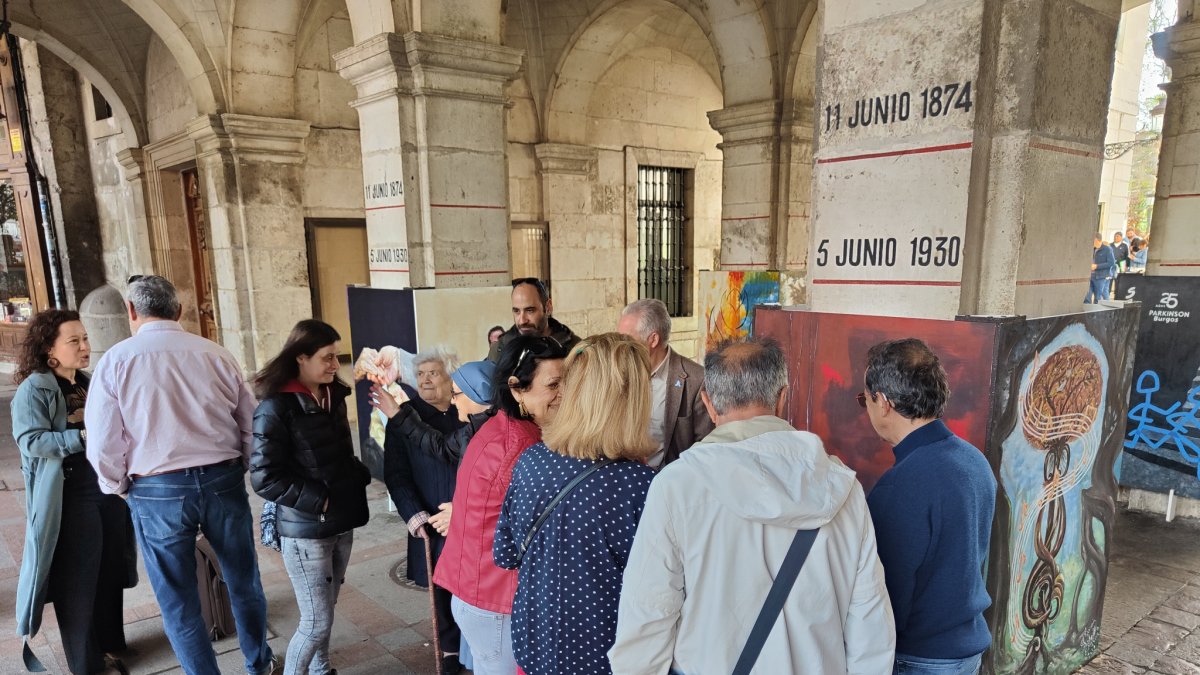 Un grupo de personas observa los cuadros pintados por enfermos y socios de la entidad. ECB