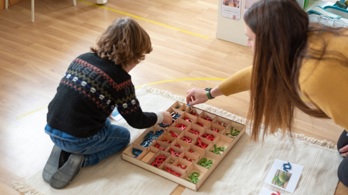 Una maestra desarrolla una actividad con un alumno.