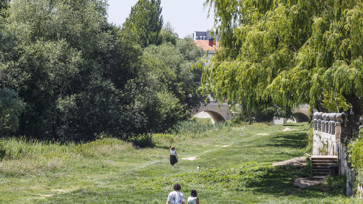 Varias personas pasean por la riberas del río Arlanzón en el centro de la ciudad.