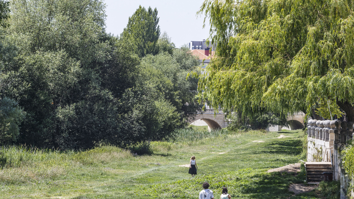 Varias personas pasean por la riberas del río Arlanzón en el centro de la ciudad.