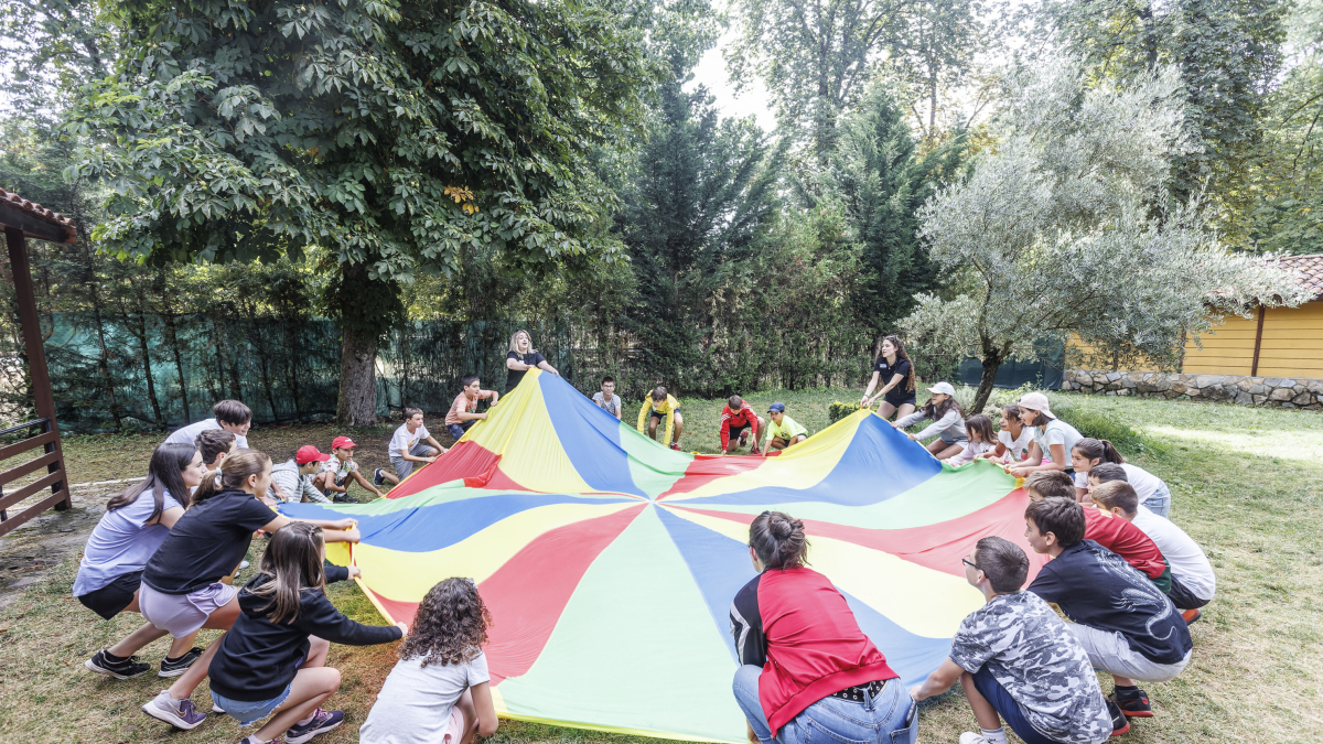 Los niños del campamento urbano de Fuentes Blancas se conocen gracias al juego del paracaídas.
