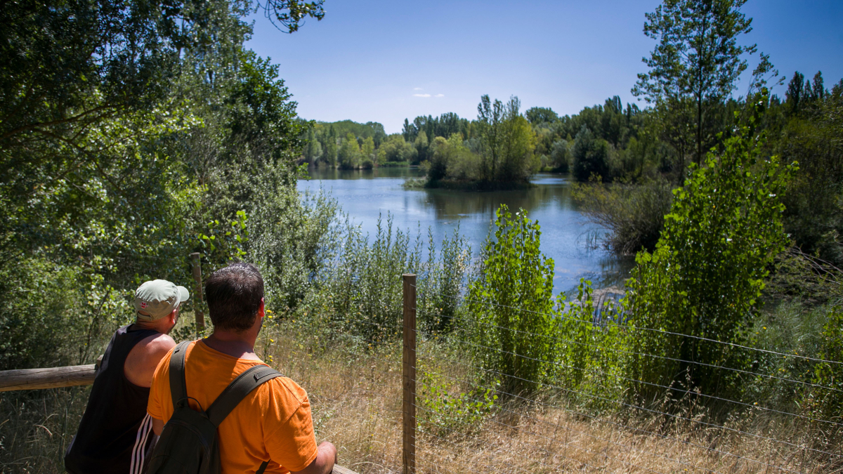 Dos excursionistas observan el humedal de Fuentes Blancas desde la plataforma de madera construida en los aledaños.