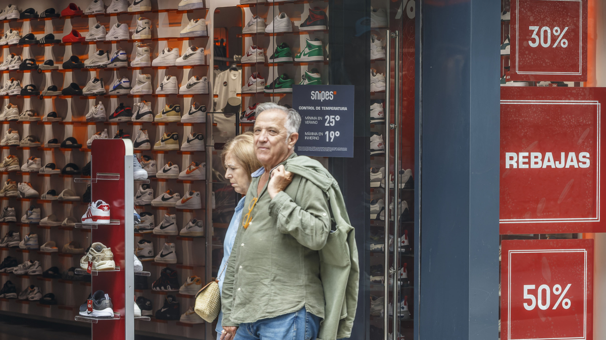 Dos personas pasan por delante de una tienda en la capital burgalesa en plenas rebajas de la temporada de verano.