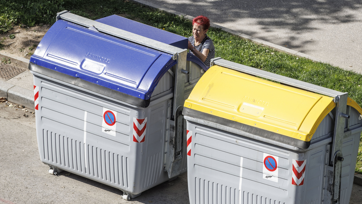 Una mujer deposita residuos en el contenedor de papel y cartón en la capital burgalesa.