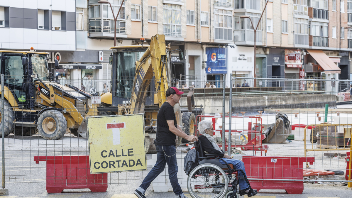 Unos vecinos cruzan un paso de peatones junto a la señalización de calle cortada.