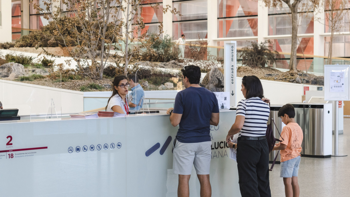 La recepcionista del MEH explica el contenido de la visita a unos visitantes.