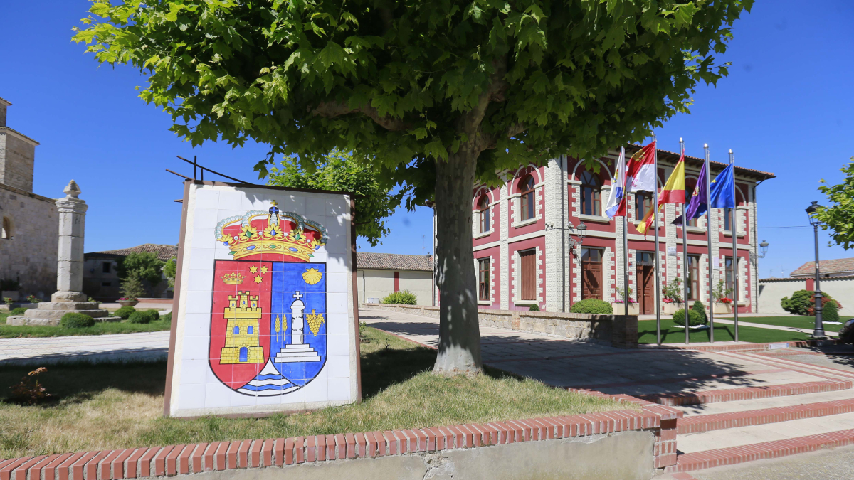 Escudo de la localidad, con el ayuntamiento al fondo.