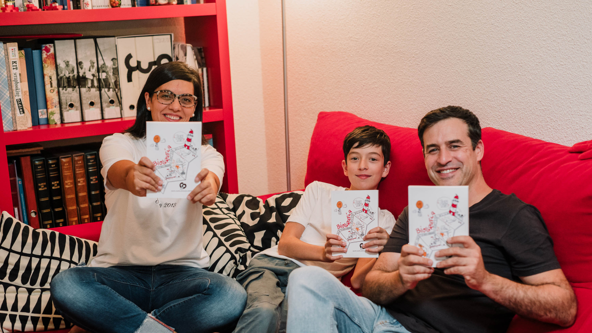 Cristina junto a Jorge, su marido, y Juan, su hijo, con el libro en la mano.