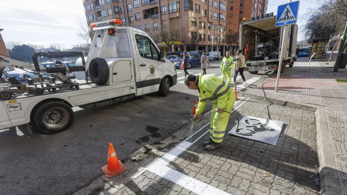 Operarios pintan el aparcamiento de motos  junto a un paso de la calle Condesa Mencía.