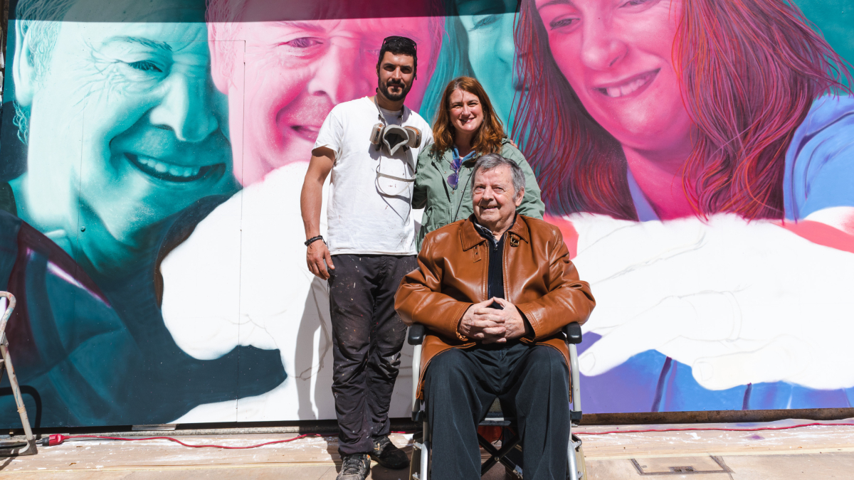 Christian Sasa con los protagonistas de su nuevo mural sobre el párkinson: Marta, terapeuta, y Julio, usuario del centro de Parkinson Burgos.