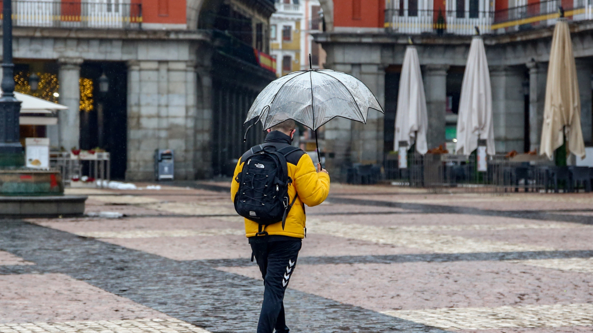 Archivo - Un hombre camina protegido por un paraguas el mismo día de la llegada del temporal ‘Gaetán’, en la Plaza Mayor de Madrid, (España), a 20 de enero de 2021.