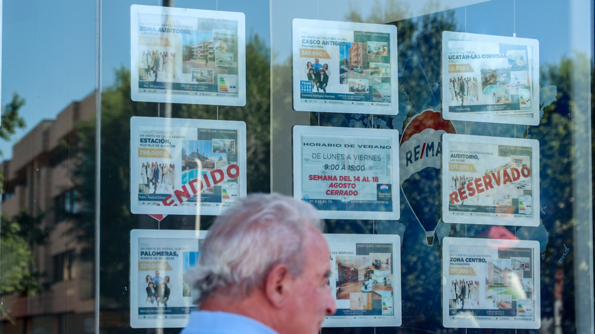 Archivo - Un hombre camina frente a un escaparate de anuncios de viviendas,