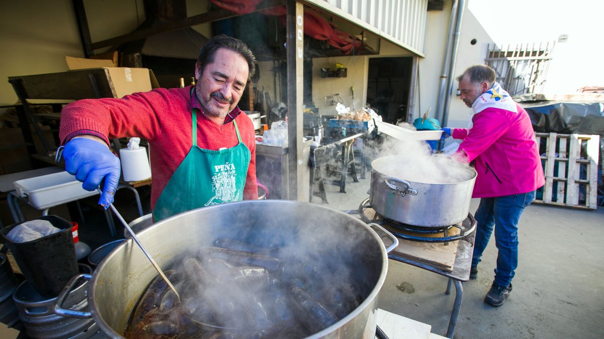 Dos miembros de una peña preparan una degustación de pinchos de 'chori y morci' en las fiestas de un barrio de Burgos.
