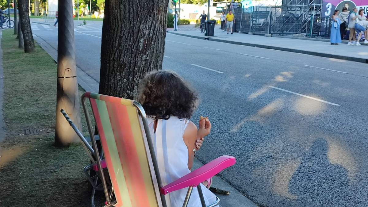 Una mujer espera sentada en una silla de playa para ver el concierto de Raphael.