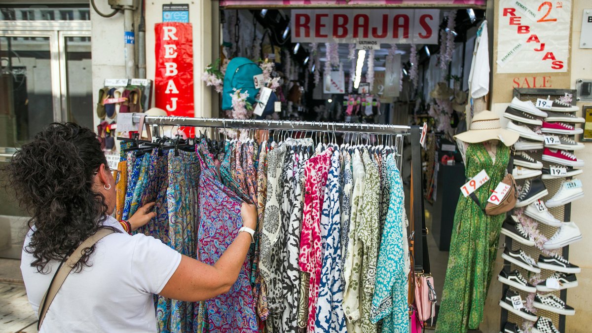 Una mujer examina unas prendas en un comercio de Burgos.