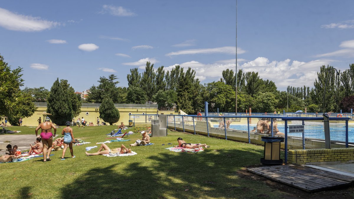 Varias familias disfrutan de la zona de sombra en las piscinas municipales de verano de El Plantío.