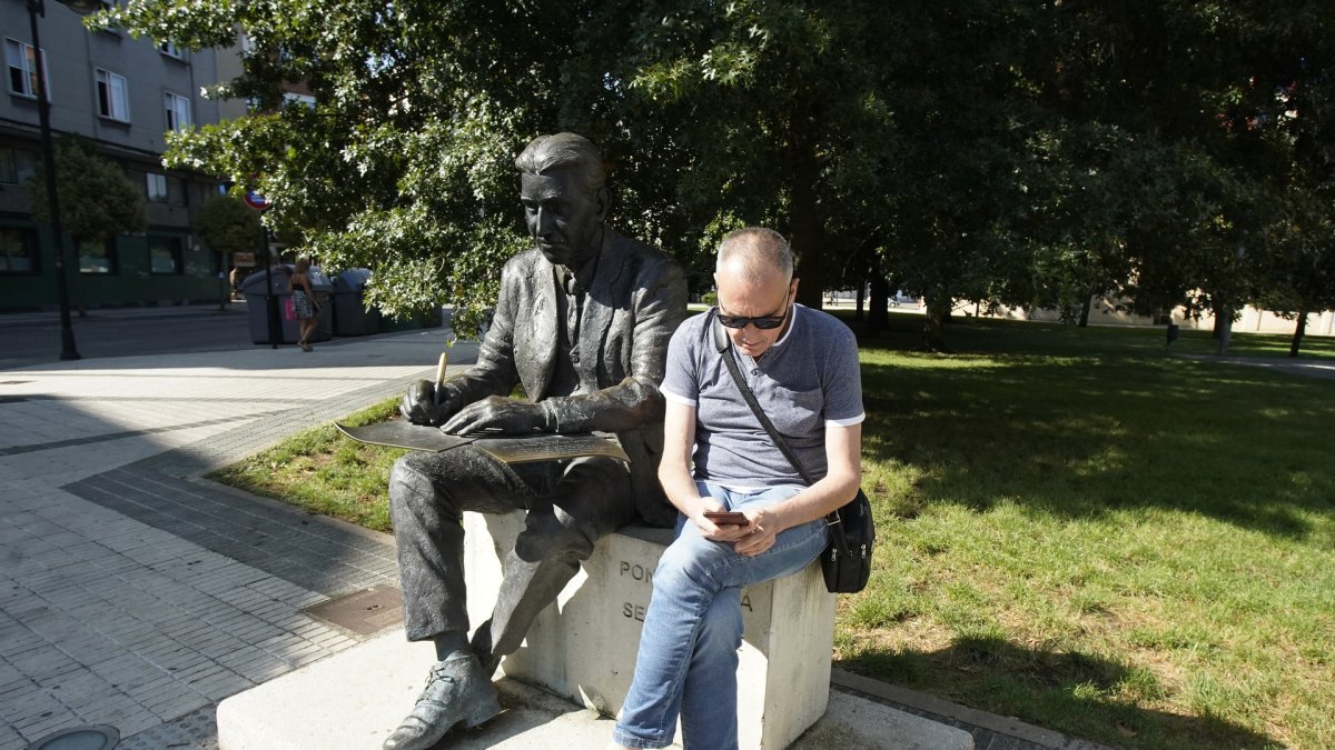 Una persona mira el móvil junto a la estatua de Miguel Fustegueras de Ponferrada