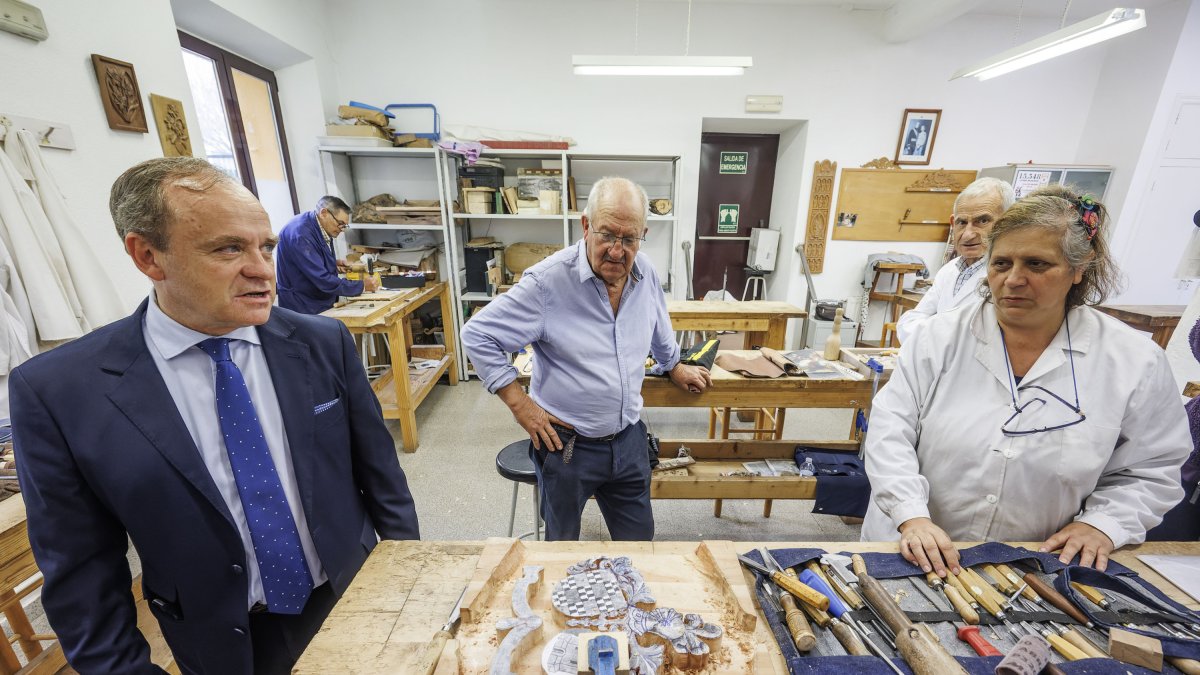 Gaspar y su profesora muestra a Martínez Acitores el escudo que está tallando en madera.