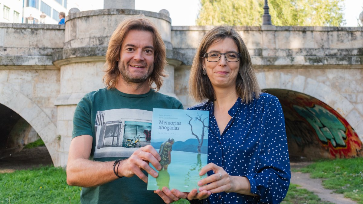 Jairo Marcos y María Ángeles Fernández, con un ejemplar de 'Memorias ahogadas', en el río Arlanzón, junto al puente San Pablo.