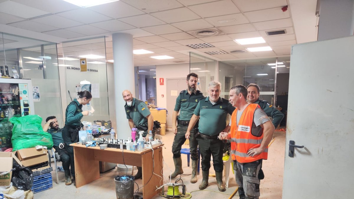 Jorge, con chaleco naranja, toma un café con agentes del puesto de la Guardia Civil en Alfafar, donde resolvió una avería.