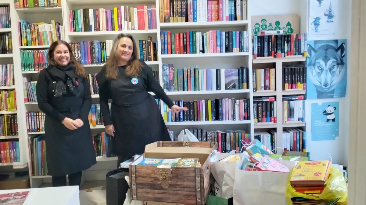 Arantzazu Suances y Sylvia Cernadas, las libreras de La Silla Mágica, con el material donado que llenaba el escaparate y parte de su librería.