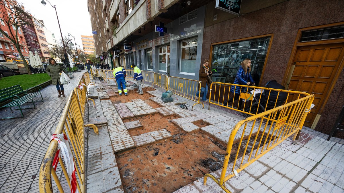 Varios peatones sortean las obras de cambio de baldosas en la calle Calzadas.