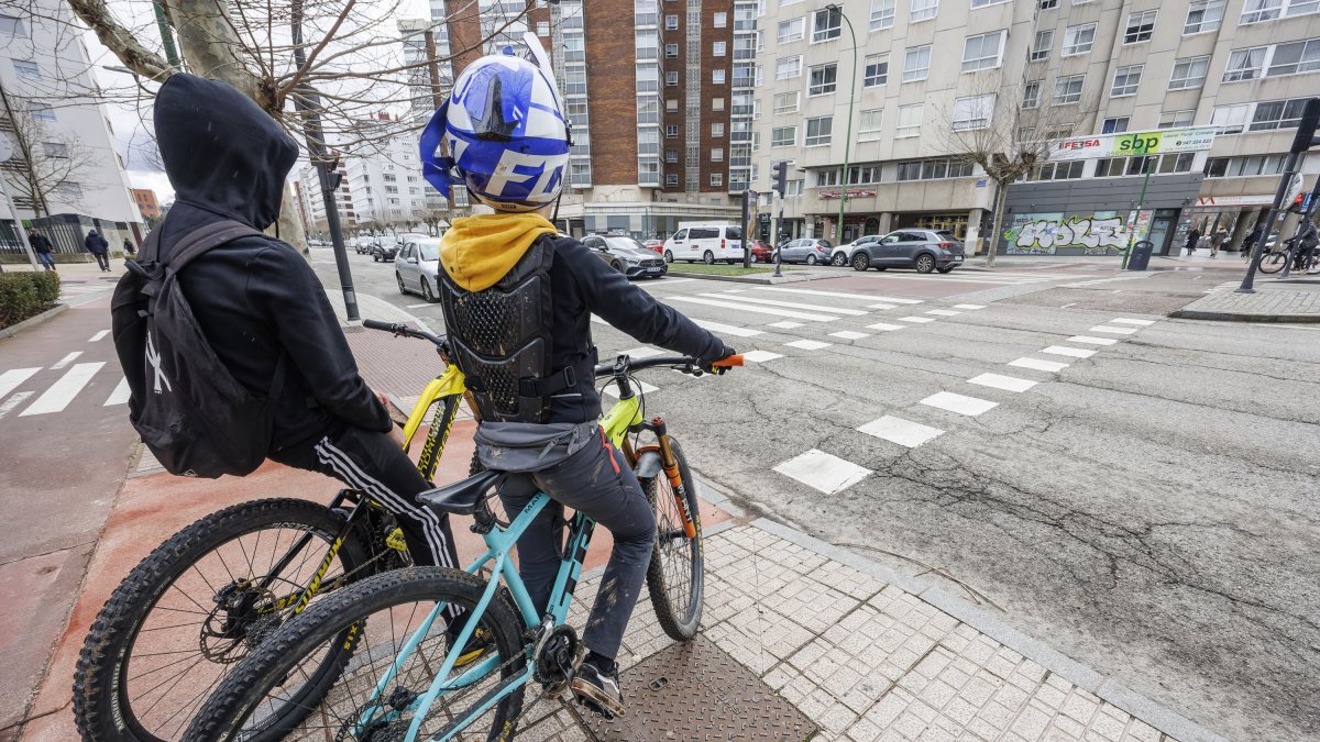 Dos jóvenes, en la avenida Cantabria, esperando a cruzar por un paso ciclista.