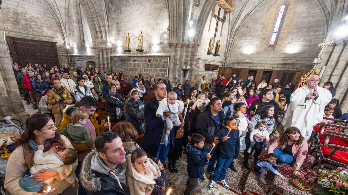Las velas y el corro ante la pila bautismal es una de las imágenes más típicas de esta tradición del barrio de Gamonal.