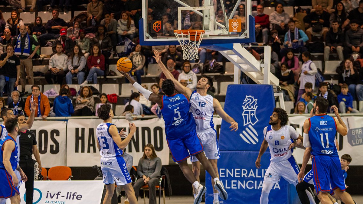 Wembi trata de colar el balón en la canasta ante la oposición de un contrario.