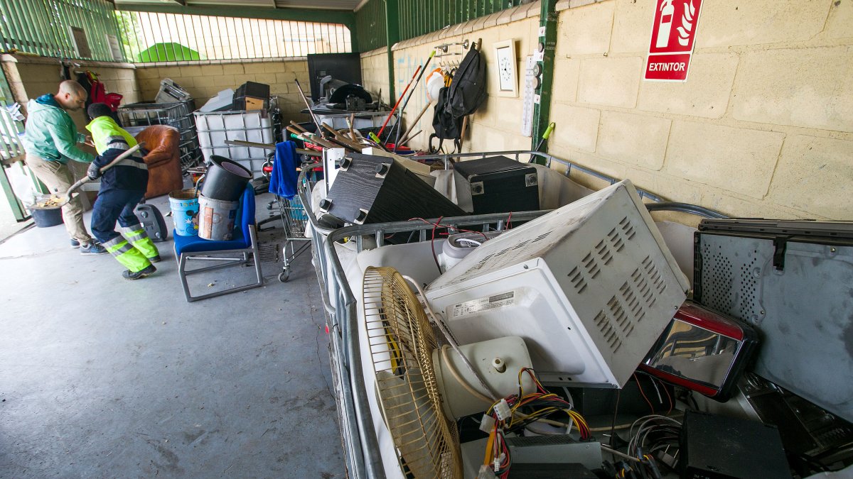 Un usuario y un trabajador con varios objetos para depositar en una zona destinada a electrodomésticos.