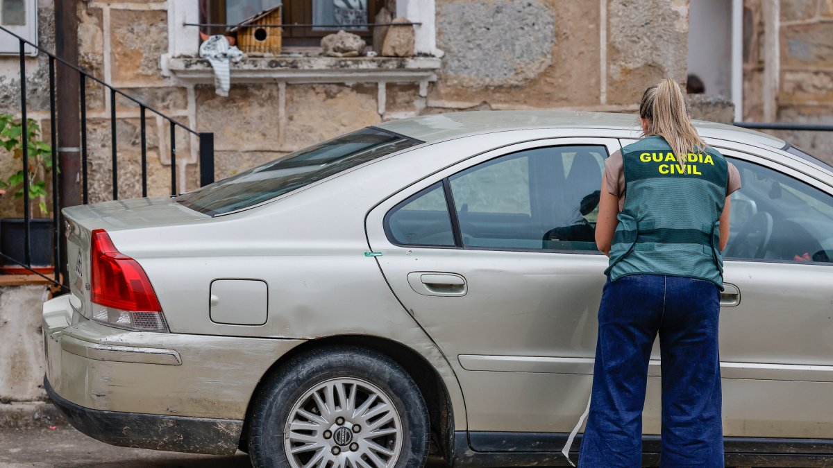 Una agente de la Guardia Civil, junto al vehículo aparcado frente a la casa de la mujer fallecida.
