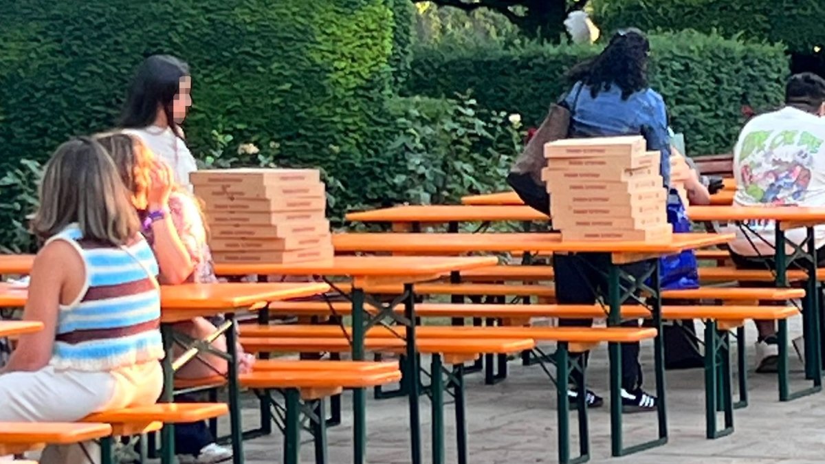 Hay quien aprovecha las mesas junto a los contenedores del Espolón para comer pizzas de fuera.
