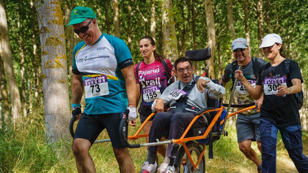 Uno de los participantes con una silla joëlette acompañado de otros inscritos en la prueba.