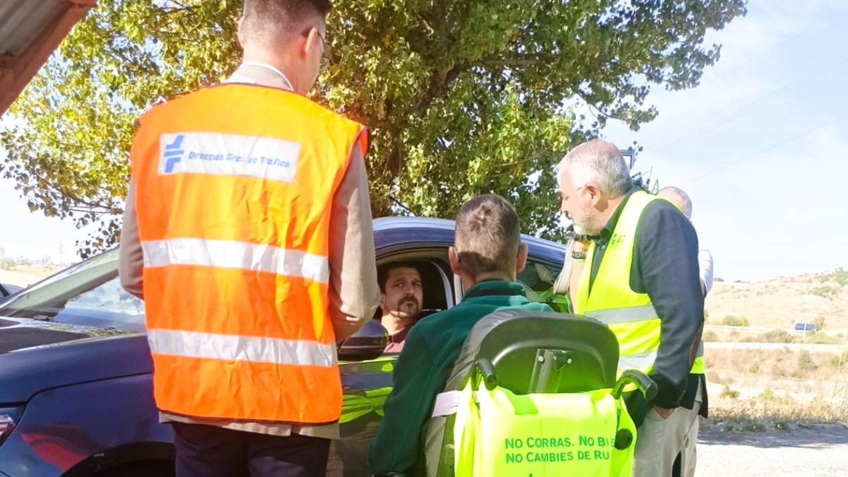 Pedro de la Fuente conversa con un conductor en las afueras de Burgos, en compañía de uno de los voluntarios de Aspaym para esta campaña.